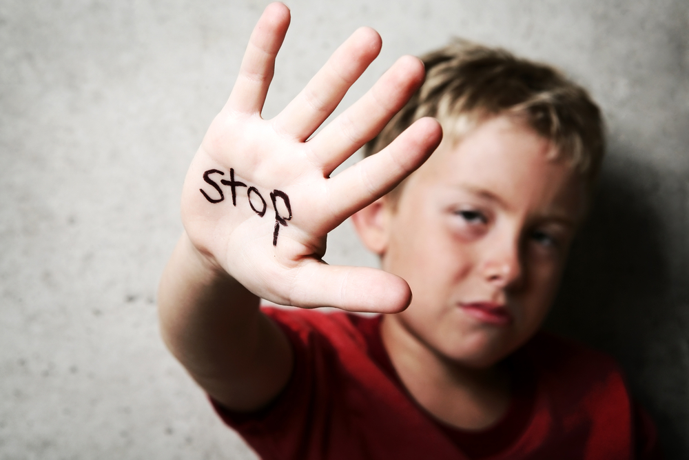 child holding hand up with word stop on his hand
