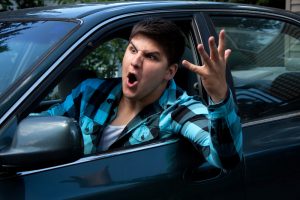 man with hand out his car window having road rage