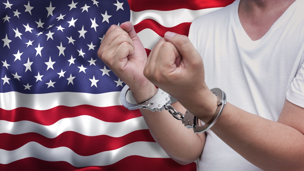 man in handcuffs with American flag in background