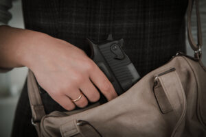 Woman with hand on gun in purse