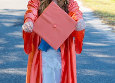 high school graduate holding graduation mortar board